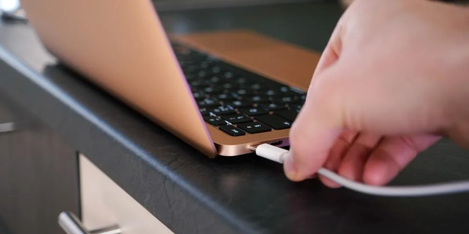 Man plugging in white USB Type C cable into USB-C port on laptop notebook com Foto stock