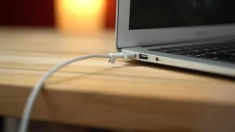 Man plugging in white USB Type C cable into USB-C port on laptop Foto stock