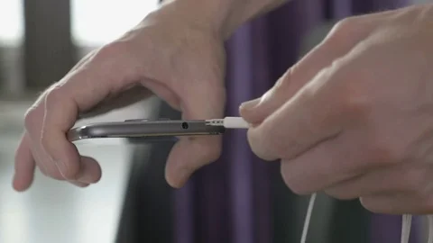 Man plugging in wire to headphone jack on a smartphone Stock Footage 81214116