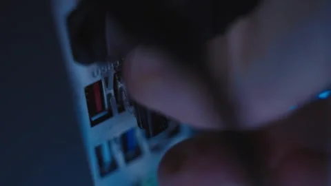 Man plugs flash drive into back of desktop computer or server at night Vidéo 334734402