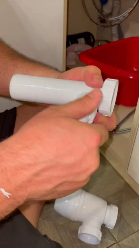 Man plumber assembling white sink drain pipe under kitchen counter. Handyman Stock Footage 340124688