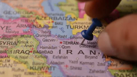 Man Pointing Blue Pin on Tehran Iran Location on Paper World Map Close Up Stock Footage 333551364