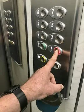 A man is pointing at a button on an elevator Stock Photos