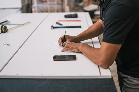 Man pointing data at a paper looking at a mobile screen in a workshop Stock Photos