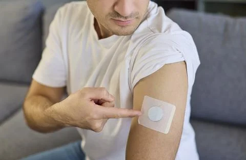 Man pointing to diabetes patch sensor on upper arm for continuous glucose care. 写真素材