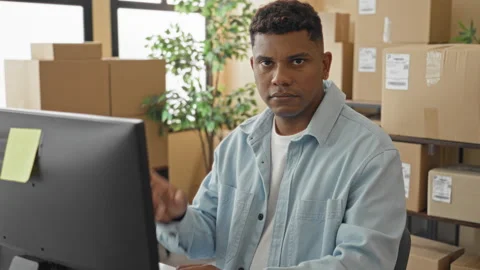 Man pointing finger at computer while typing beside stacked shipping boxes .. Stock Footage 347818491