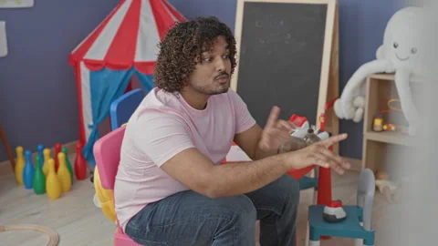 Man pointing finger at a toy on a play table in a kindergarten building, we.. Stock Footage 337404758