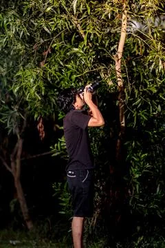 Man pointing his camera at the trees to take photo. Photo from back side of.. Stock Photos