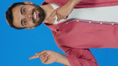 Man pointing to the left of the screen with her fingers, on a blue background. Stock Footage 143913449