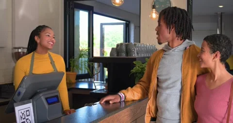 Man pointing at menu board, couple leaning in coffee shop, barista explaining Stock Footage 337537237