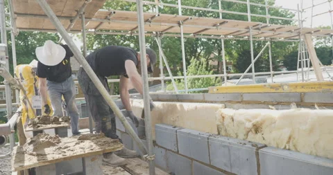 Man pointing mortar brickwork surrounded by scaffolding Stock Footage 246381980