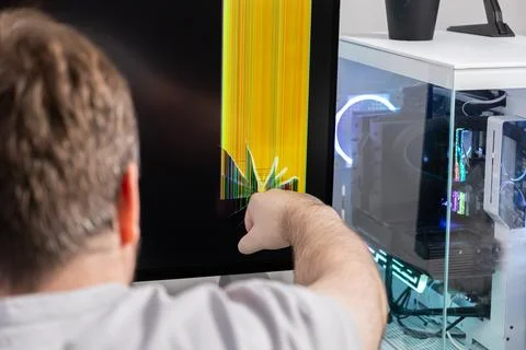 Man pointing at a severely broken computer monitor with colorful vertical l.. Foto stock