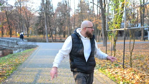 Man pointing towards something interesting while walking on path in autumn park Stock Footage 346726107