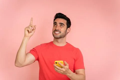 Man pointing upwards while holding mobile phone. Stock Photos