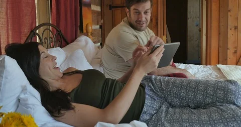 Man pointing at a woman's digital tablet while spending time together in bed Stock Footage 107266215