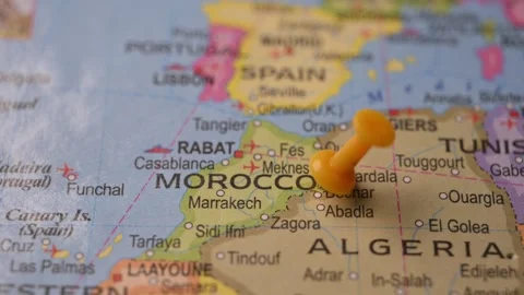 Man Pointing Yellow Pin on Morocco Location on Paper World Map Stock Footage 333552884