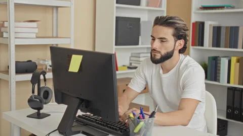Man points finger to camera at computer desk in an office, smiling while ty.. Stock Footage 337371898