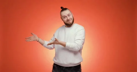 Man points hands aside and pretends he gives something on red background. Stock Footage 149034074