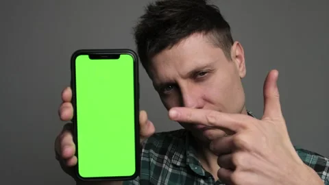 A man points to mockup on green screen phone with a confident expression, gestur Stock Footage 296891263