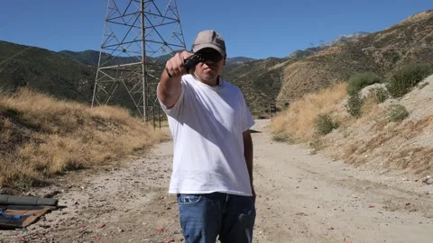 Man points sideways pistol towards camera in a threatening manner Stock Footage 249016621