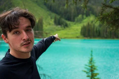 Man points toward the mountain with emerald-green water in the background Stock Photos