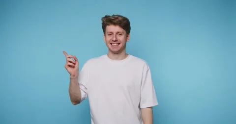 Man points upwards with a playful expression, radiating positivity and exci.. Stock Footage 313280682