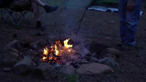 A man poking a campfire with a stick to stoke the flames Stock Footage 283683214