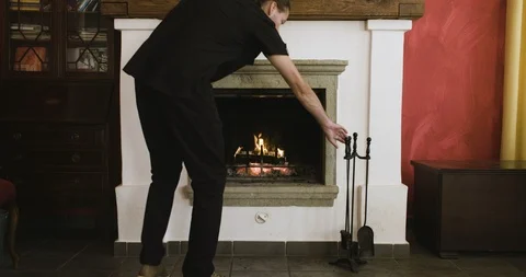 Man poking a fire burning In a fireplace Stockbeeldmateriaal 97873014