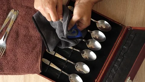 Man polishing a fork with cloth, cleaning cutlery set in wooden box, househol Stock Footage 315213408