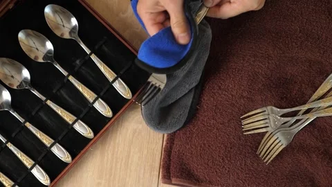 Man polishing a fork with cloth, cleaning cutlery set in wooden box, househol Stock Footage 315213770