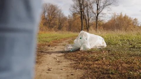 Man pollutes the environment with plastic. Uncultured young man in nature kicks Stock Footage 120872145