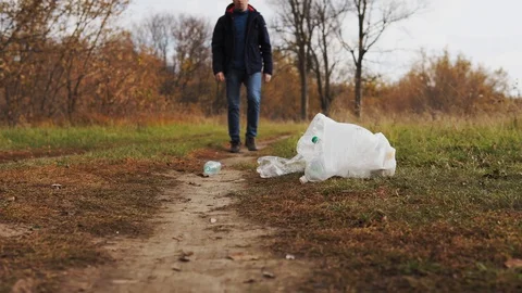 Man pollutes the environment with plastic. Uncultured young man in nature kicks Stock Footage 120872180