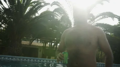 A man in the pool against the light of the sun happy with his can of beer Stock Footage 170022664