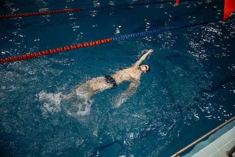 Man in the pool. Floating on his back. A swimmer trains in the pool on the track Stock Photos
