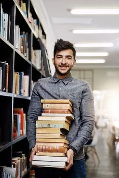 Man in portrait, college student with stack of books in library and research 写真素材