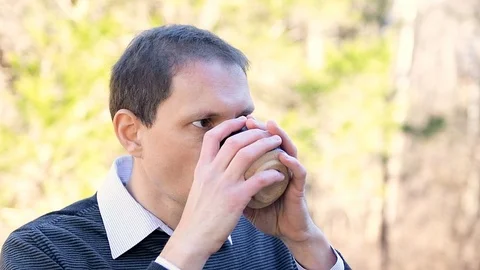 Man portrait face closeup drinking green tea outside in garden in slow motion Stock Footage 107937727