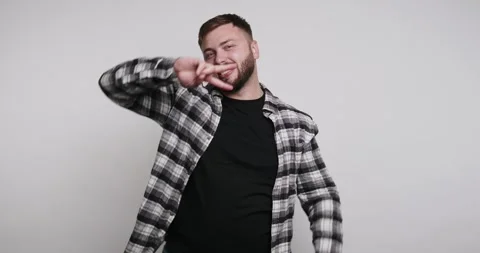 Man poses and smiles while showing peace sign in front of plain background Stock-Footage 326798127
