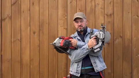 A man poses with electric saws in his hands 4K Stock Footage 291263802