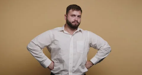Man poses with hands on hips against a plain background showing a serious e.. Stock-Footage 326797742