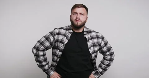 Man poses with hands on hips in black shirt and plaid jacket against plain .. Stock-Footage 326798350