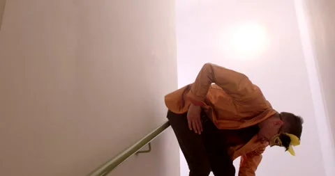 Man Poses Proudly in Orange Jacket at an Intriguing Staircase Stock Footage 316549606