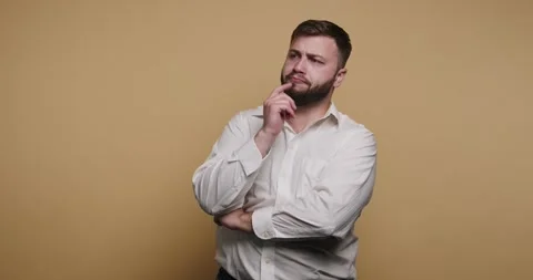 Man poses thoughtfully in front of a yellow background during a casual moment Stockbeeldmateriaal 326797713