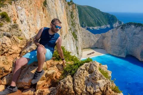 Man posing above Navagio beach in Zakynthos, Greece. Foto stock