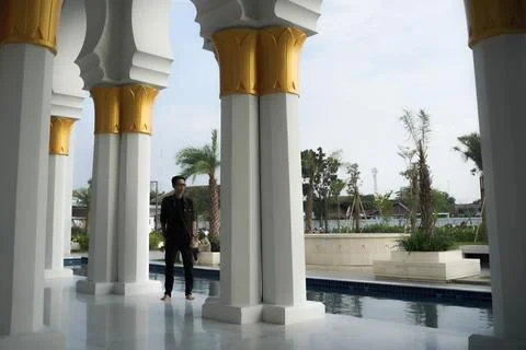 A man posing between the pillars of the beautiful mosque, at the Great Mosq.. Stock Photos