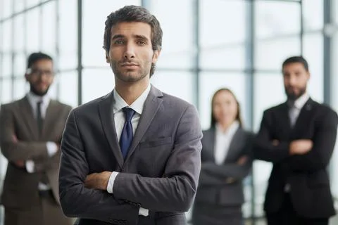 A man posing for the camera with his arms crossed in front of his colleagues in Stock Photos