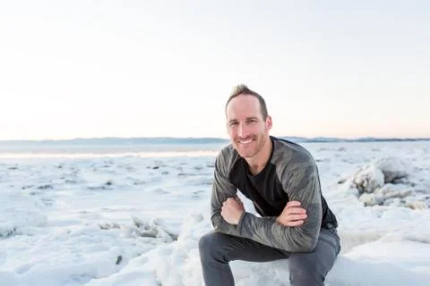 Man posing at camera with an iceberg in the background Stock-Fotos