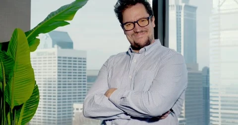 Man Posing Confidently in Office with City View 스톡 동영상 323680103