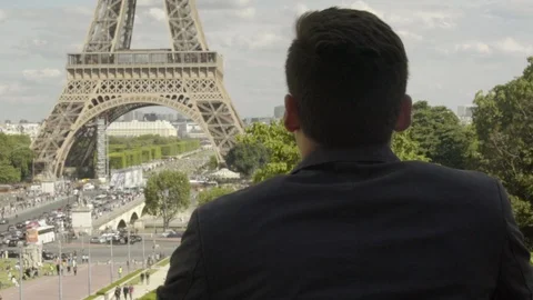 Man posing at the Eiffel Tower after work, with a black jacket, brown hair and Stock-Footage 111924004