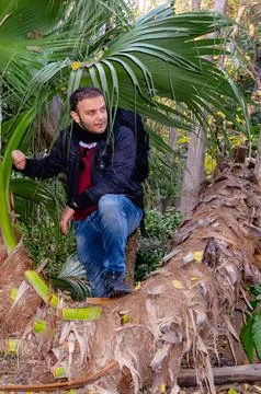 Man posing on fallen palm tree in National Garden Athens, Greece. Stock Photos