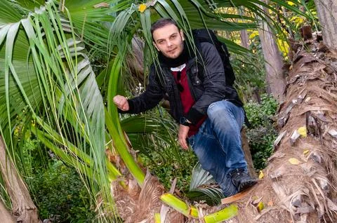 Man posing by fallen palm tree in National Garden Athens, Greece. Foto stock